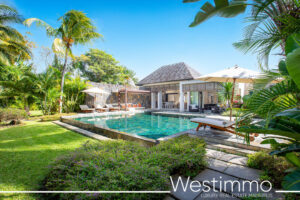 Exterior view of a 415 m² villa in Mauritius, surrounded by a tropical garden with royal palms, infinity pool and views of the lagoon and Anahita golf course.