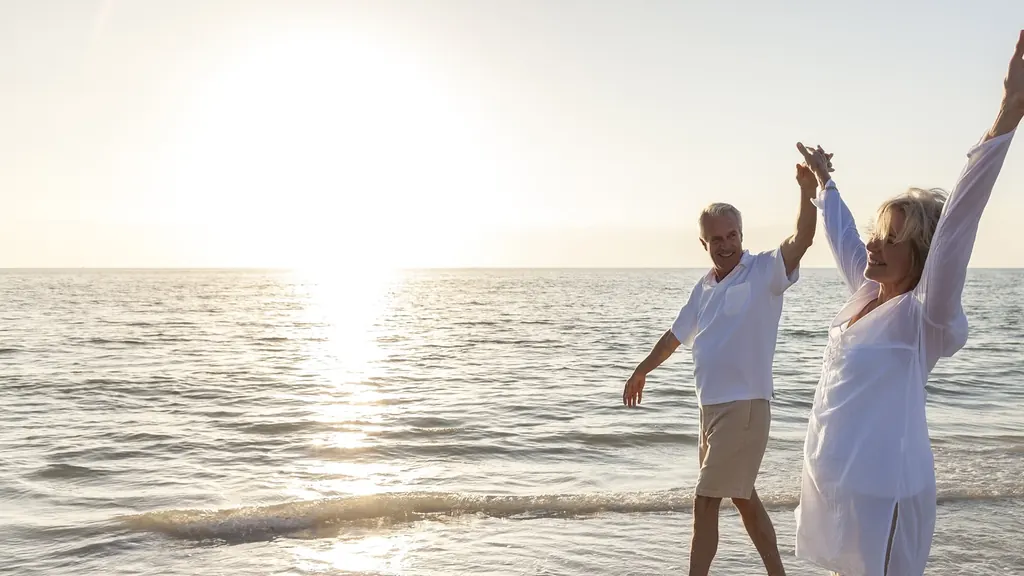 Couple de retraités qui dansent au bord de la mer, main dans la main